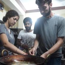 three people standing in a kitchen with a bowl