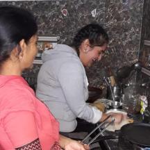 two women standing in a kitchen preparing food