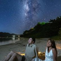 a man and a woman sitting on the beach at night