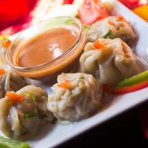 a plate of food with dumplings and a dipping sauce