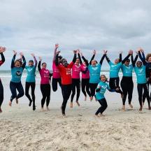a group of people jumping in the air on the beach