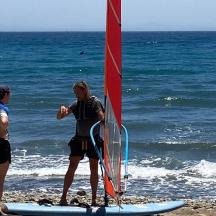 a group of people standing on the beach with a sail