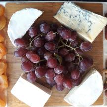 a tray filled with cheese and grapes and other foods