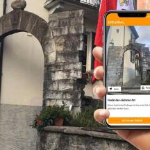 eine Person, die ein Mobiltelefon vor einem Gebäude hält