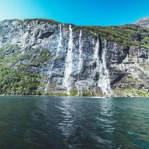 a waterfall on a mountain next to a body of water