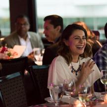 cilvēku grupa sēž pie galda ar vīna glāzēm