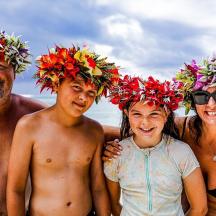 a group of people wearing flower hats on the beach