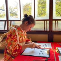 a woman in a kimono writing at a table