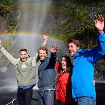 a group of people standing in front of a rainbow