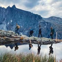 a group of people walking on a rock near a mountain