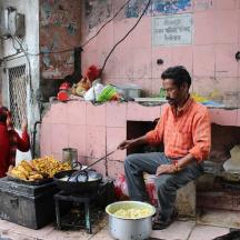 a man sitting in front of a stove with food