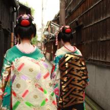two geisha walking down a street wearing kimonos