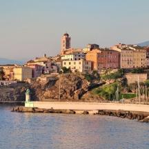 a group of buildings on a hill next to a body of water