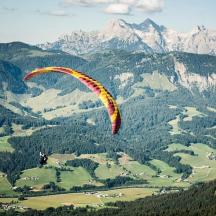 eine Person fliegt mit einem Fallschirm über einen Berg