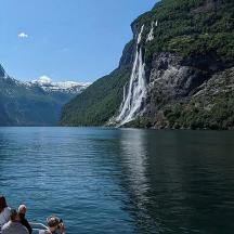 a group of people on a boat in front of a waterfall