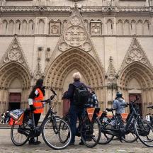 a group of people standing with bikes in front of a building