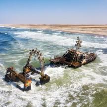 a boat in the ocean with two dredgers in the water