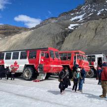 eine Gruppe von Menschen steht im Schnee neben Bussen