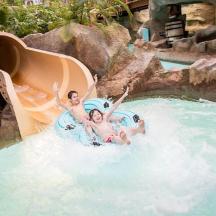 due persone che vanno su uno scivolo d'acqua in una piscina