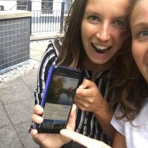 two women are holding up a cell phone