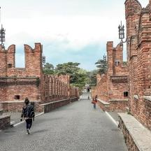 a person walking down a street between brick buildings