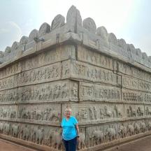 a woman standing in front of a large stone wall
