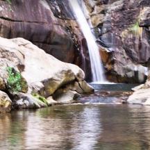a waterfall in a pool of water next to a river