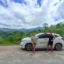 a man and a woman standing next to a white car
