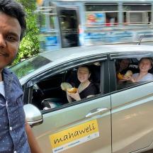 a man standing next to a car with people eating food