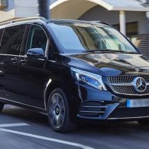 a black mercedes benz van driving down a street