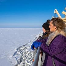two women are standing on a boat in the snow