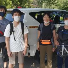 four people wearing masks standing in front of a van