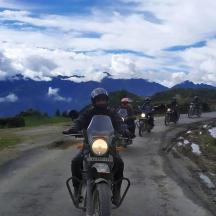 a group of people riding motorcycles down a dirt road