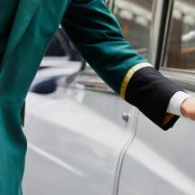 a man in a green suit opening a car door