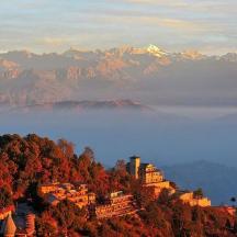 a town on a hill with mountains in the background