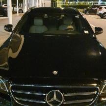 Acedes Benz auto geparkeerd op een parkeerplaats met twee personen