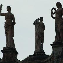 tres estàtues de persones a la part superior d'un edifici