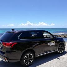 a black car parked on a beach near the ocean