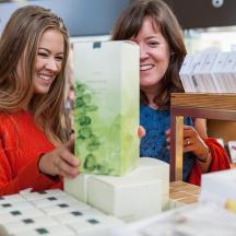 two women are smiling while looking at a cake
