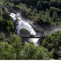 a group of people standing on a bridge over a waterfall