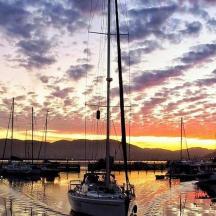 eine Gruppe von Booten, die bei Sonnenuntergang in einem Yachthafen angedockt sind