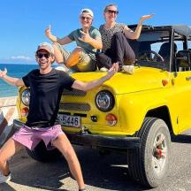 a group of people sitting on the back of a yellow jeep