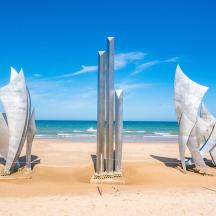 a sculpture on a beach with the ocean in the background