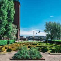 a garden with hedges and bushes in front of a building