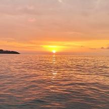 a sunset over a body of water with the sun setting