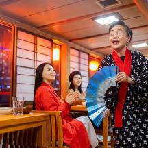 a group of women sitting in a restaurant with a man holding an umbrella