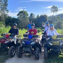 a group of people sitting on atvs on a dirt road