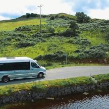 a van driving down a road next to a hill