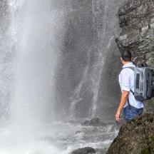 Ein Mann steht auf einem Felsen vor einem Wasserfall
