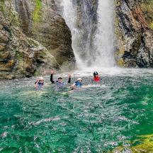 tres persones a l'aigua davant d'una cascada